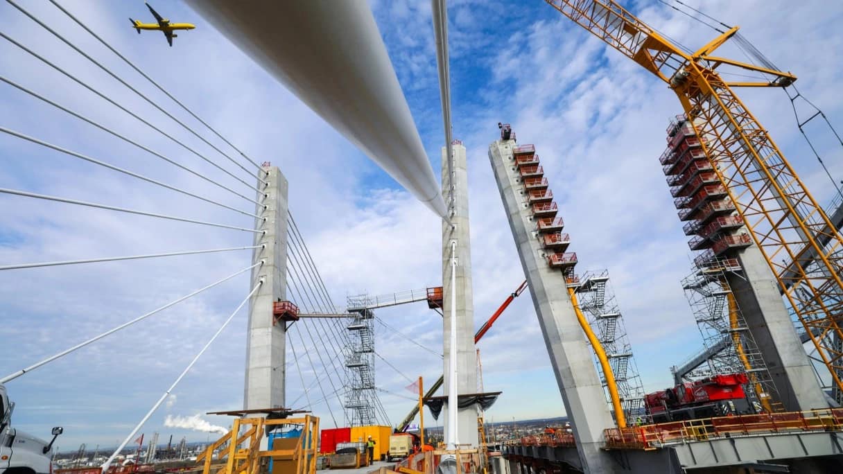 bridge in construction with a flying plane on the sky